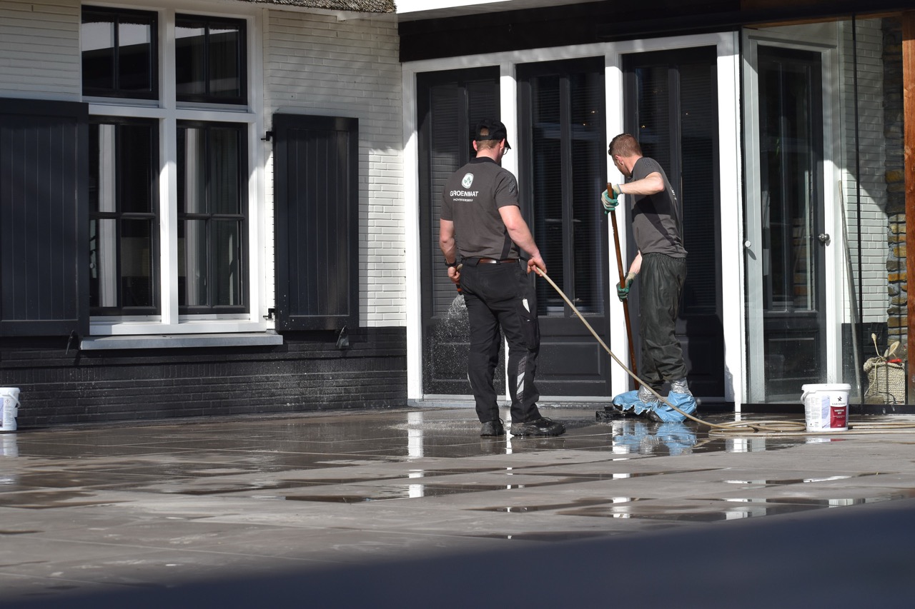 Twee medewerkers van Groenmaat werken samen aan een terras
